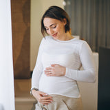 joven embarazada de pie junto la ventana en casa portada TPNI casos especiales PLUS